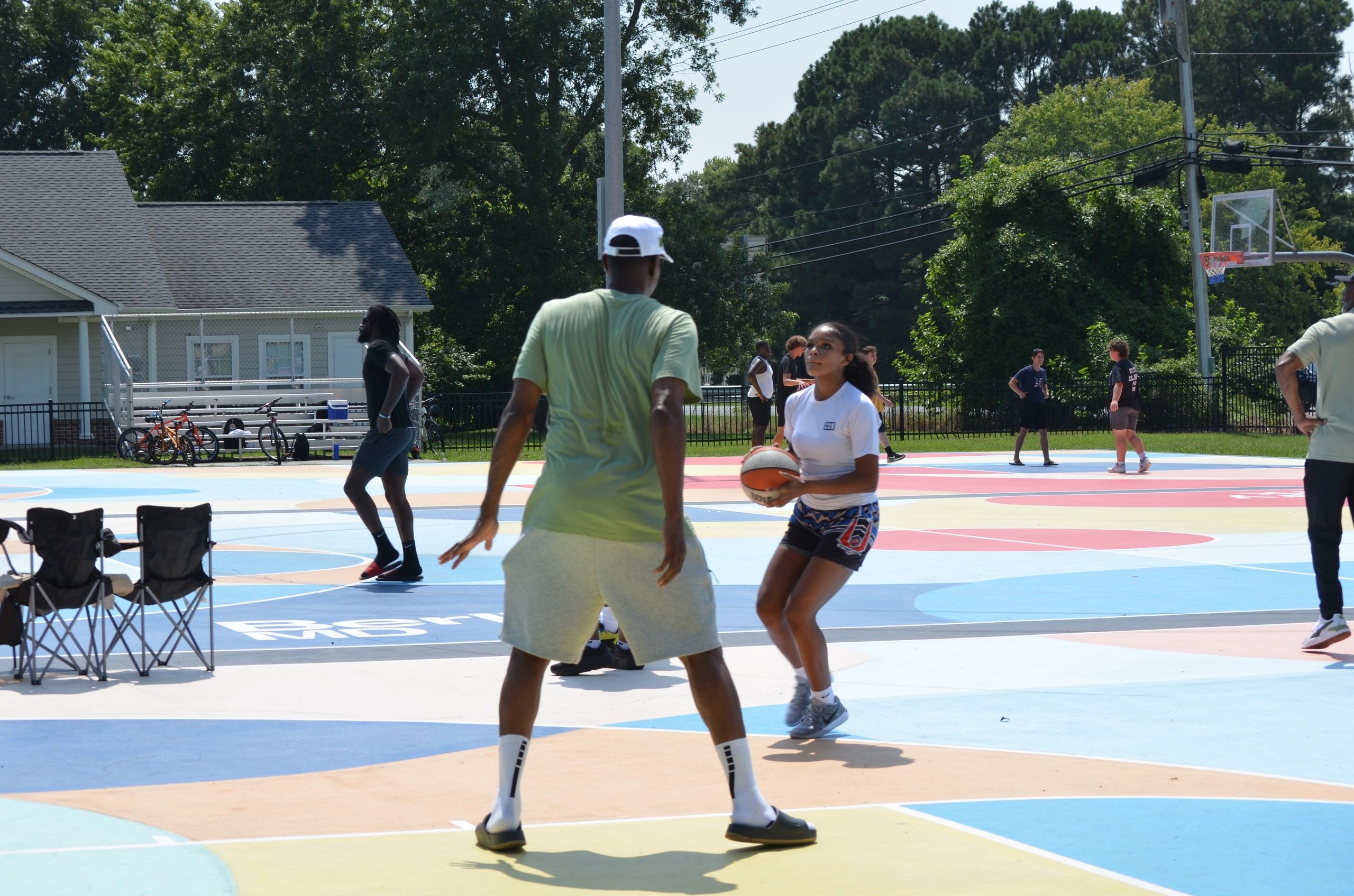 Community members playing basketball on a vibrant outdoor court at a Driven Over Given event