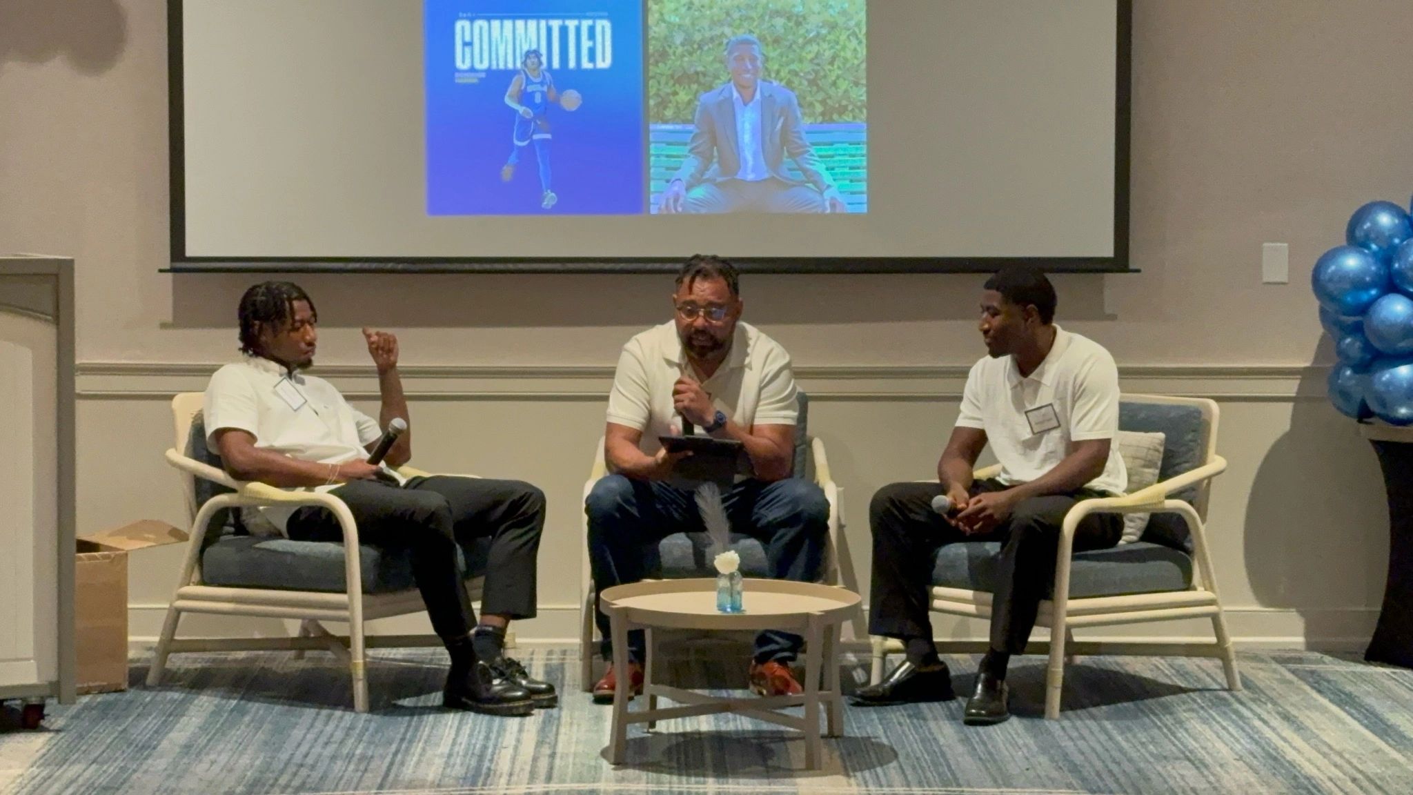 Panel discussion at a Driven Over Given event with three men seated on stage