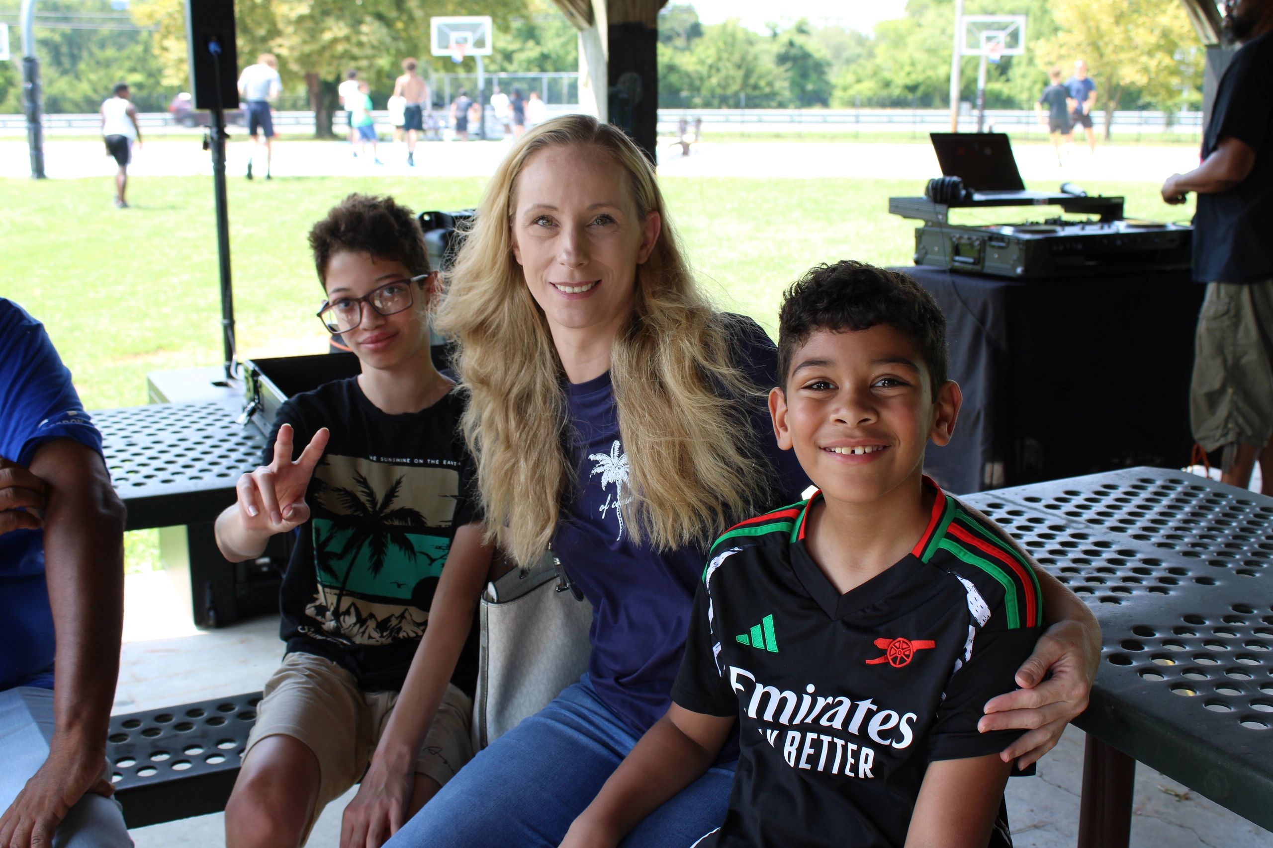 A woman and two young boys smiling together at a Driven Over Given community event